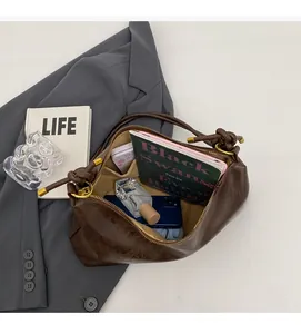 Macro detail of the spacious interior of a dark brown leather hobo bag with daily items