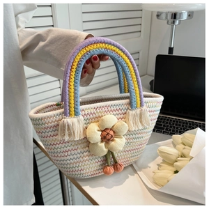 Détail du sac à main tissé blanc avec poignée arc-en-ciel et breloque fleur