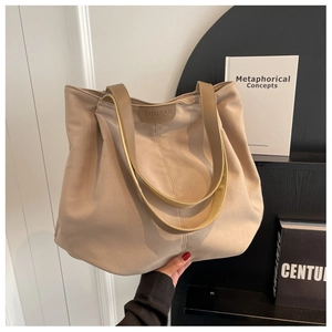 Detail of minimalist beige canvas tote bag with brown shoulder strap and logo patch