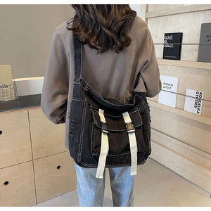 Close-up of black canvas crossbody bag with white straps and buckles on back of model