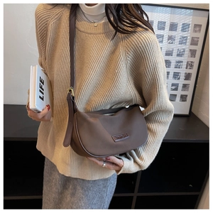 Brown nylon half-moon crossbody bag shown on a model with adjustable strap and zip closure