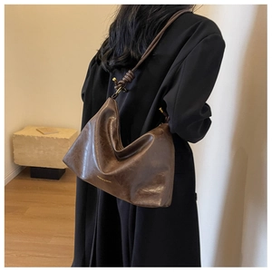 Close-up of vintage brown leather underarm bag with gold logo and knotted strap detail
