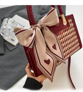 Close-up of a retro red crossbody bag with houndstooth panel and silk scarf detail