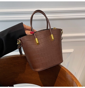 Close-up of brown crocodile texture bucket bag with gold hardware and top handles