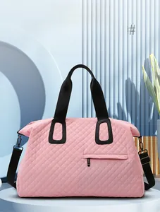 Detail of pink quilted large capacity travel bag with black straps and fashion accents