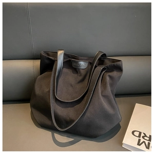 Macro view of durable black canvas tote bag with leather straps and logo detail