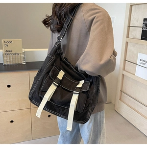 Detail of black canvas messenger bag featuring white stitching and frayed edge textures