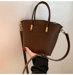Detailed view of dark brown faux crocodile leather tote bag with gold metal hardware