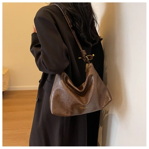 Detail of hobo bag with knotted shoulder strap and vintage leather texture on model