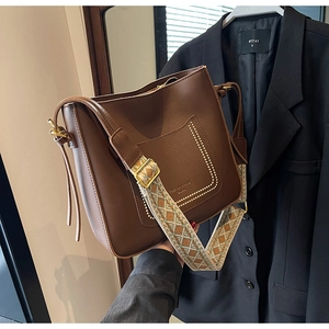 Detail of dark brown leather bucket bag featuring ethnic jacquard wide shoulder strap