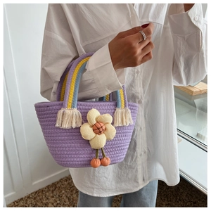 Dettaglio borsa a secchiello in maglia lavanda con ciondolo a fiore e manico
