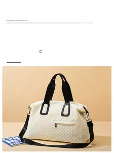 Detail of cream quilted travel bag with black handles and front zipper pocket