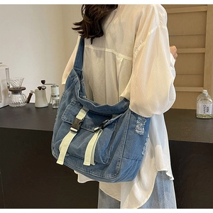 Détail du sac bandoulière en denim bleu avec texture effilochée et sangle contrastée
