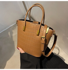 Detail of brown crocodile embossed texture and gold metal hardware on handbag