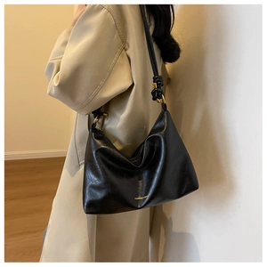 Detail of black faux leather tote with golden ring hardware and minimalist gold text