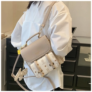 Détail du sac à dos vintage beige avec motifs d'ours et pendentif sur un mannequin
