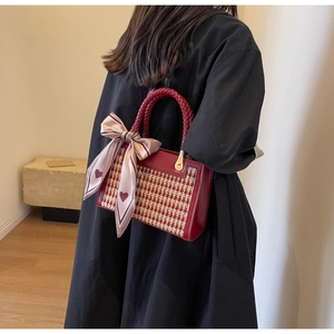 Detail of red houndstooth handbag with woven handle and heart silk scarf decoration