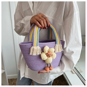 Dettaglio borsa a secchiello viola intrecciata con manici arcobaleno e fiore