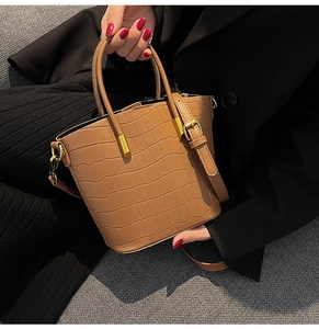 Detail of brown crocodile embossed bucket bag with gold-tone hardware and sturdy handle
