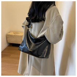Detail of knot shoulder strap with gold ring hardware on black hobo shoulder bag