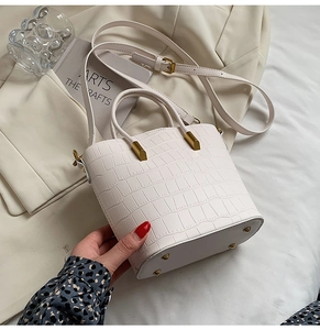 Detail of white crocodile embossed texture bucket bag with elegant gold hardware