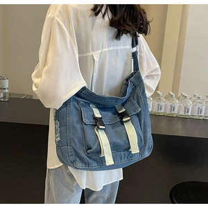 Détail de la besace en jean bleu montrant la texture effilochée et les boucles réglables