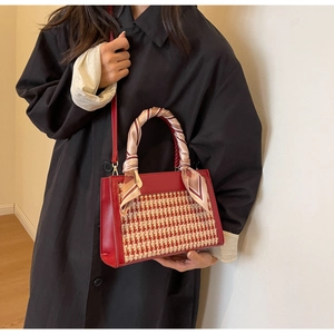 Detail of red leather crossbody bag featuring houndstooth fabric and silk scarf handle