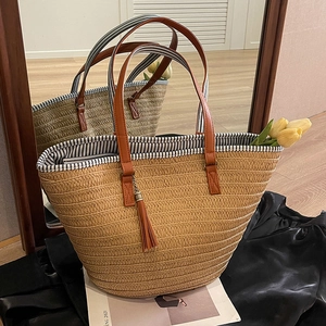 Straw tote bag with leather handles and tassel pendant reflected in home mirror