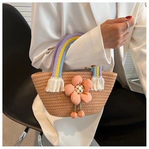 Détail du sac seau tissé avec poignée arc-en-ciel et décoration florale orange vif