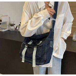 Detail of navy denim messenger bag with contrast stitching and adjustable wide strap