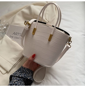 Close-up of white crocodile pattern bucket bag with golden hardware and handles