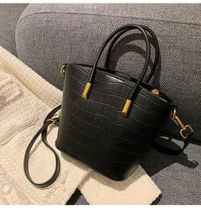 Detailed macro of black crocodile pattern bucket bag with gold metal hardware