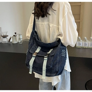 Détails du sac bandoulière en denim bleu avec doubles boucles et bords effilochés