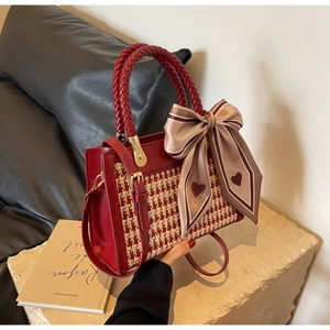 Detail of red houndstooth crossbody bag with woven handle and silk scarf accessory