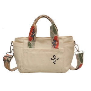Versatile cream canvas tote bag with colorful printed straps and front patch pocket