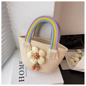 Détail du sac seau tressé avec anses arc-en-ciel, fleur décorative et pompons doux
