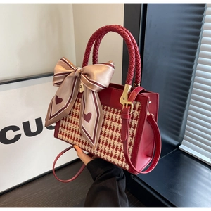 Detail of red tweed handbag featuring a large satin bow and woven handle accents
