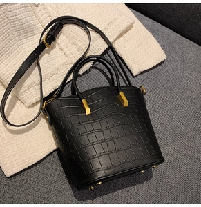 Detailed view of black crocodile pattern leather bucket bag with golden hardware