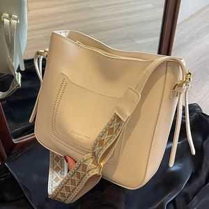 Creamy white bucket bag with wide ethnic strap and stylish leather finish in mirror view