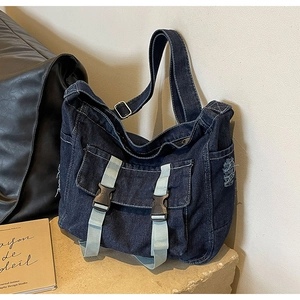 Détail d'un sac bandoulière en denim bleu foncé avec boucles et texture de franges usées