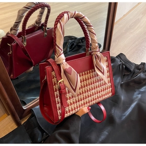 Detail of burgundy crossbody bag with houndstooth panel and heart scarf handle