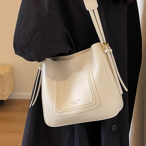 Fashionable cream bucket bag with wide strap and gold rivet pocket detail