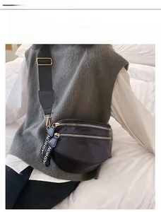 Detail of black nylon crossbody bag with dual golden zippers and fashion webbing pulls