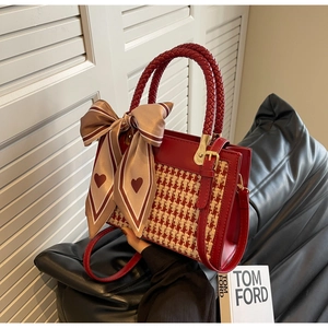 Detail of red houndstooth handbag with woven handle and decorative heart scarf