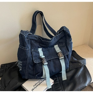 Détail du cabas en jean vieilli avec sangles en sangle bleue et fermeture par boucle