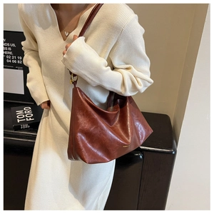 Close-up of a deep reddish-brown leather tote bag with subtle golden branding and zipper