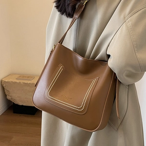 Chic brown leather bucket bag with pearl trim and gold lettering on shoulder strap