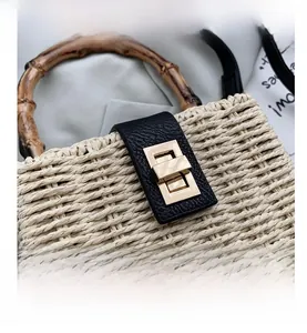 Detail of woven straw handbag featuring bamboo handle and leather gold twist lock