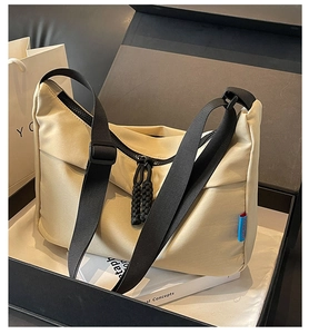 Detailed shot of beige nylon crossbody bag with black wide strap in premium gift box set