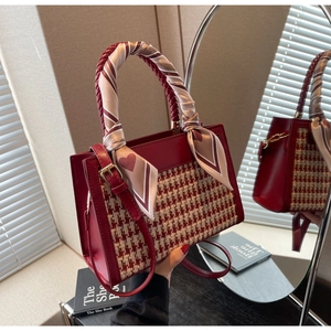 Detail of red houndstooth handbag with leather texture and silk scarf handle decoration